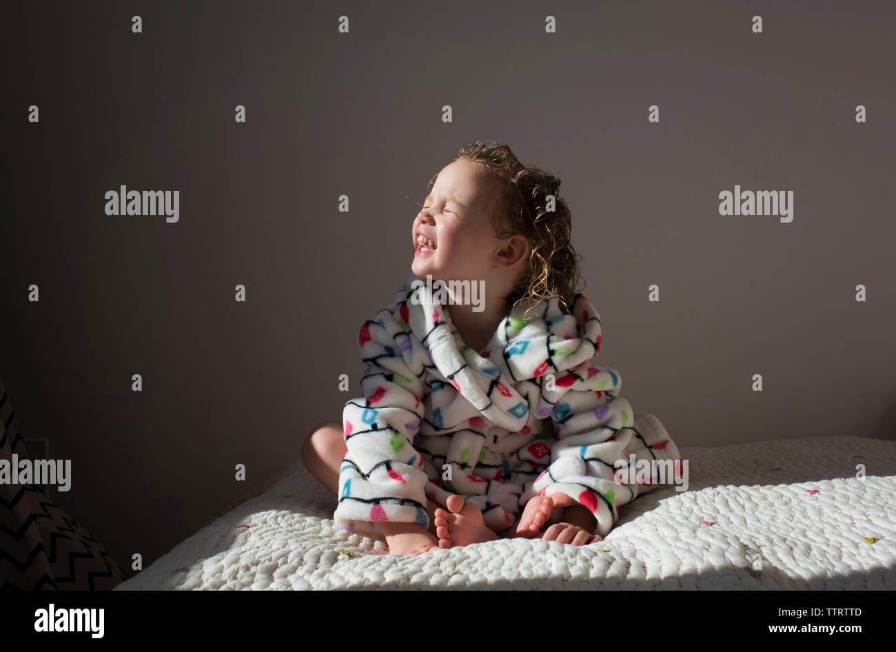 Smiling girl avec les yeux fermés alors qu'assis sur le lit de bronzage à la maison Banque D'Images