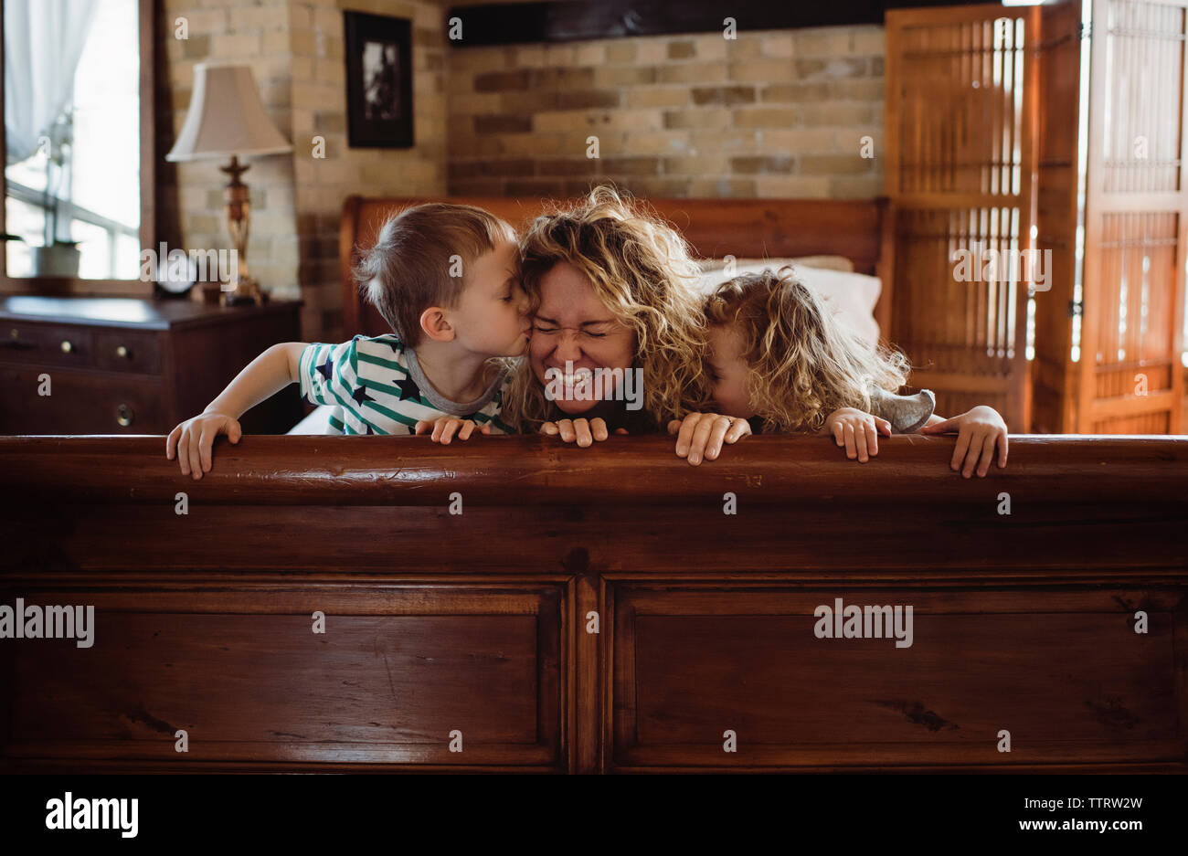 Heureux Enfants baisers mère sur le lit chez lui Banque D'Images