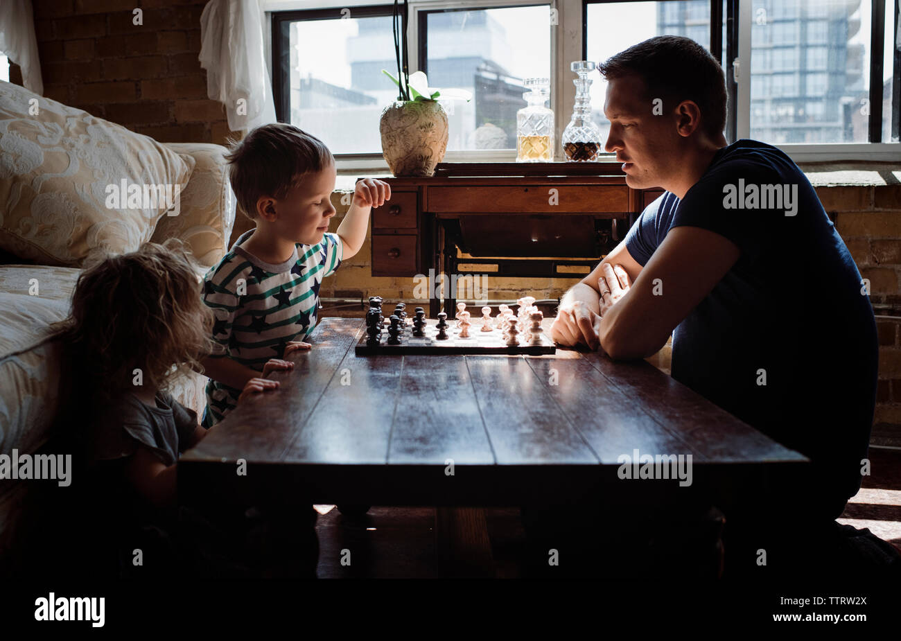 Père jouer aux échecs avec les enfants sur la table à la maison Banque D'Images