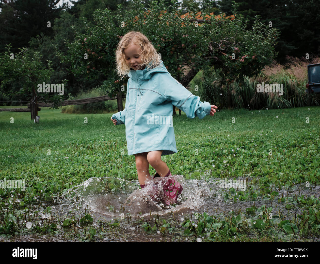 Playful girl splashing water en flaque à verger Banque D'Images