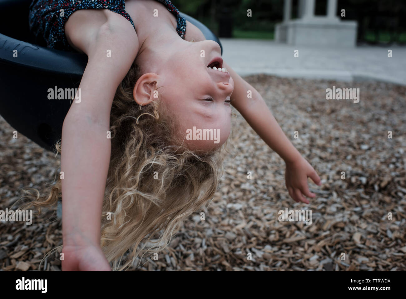 Carefree cheerful girl lying on l'équipement de jeu d'extérieur tout en jouant au jeu pour enfants au cours de l'automne Banque D'Images