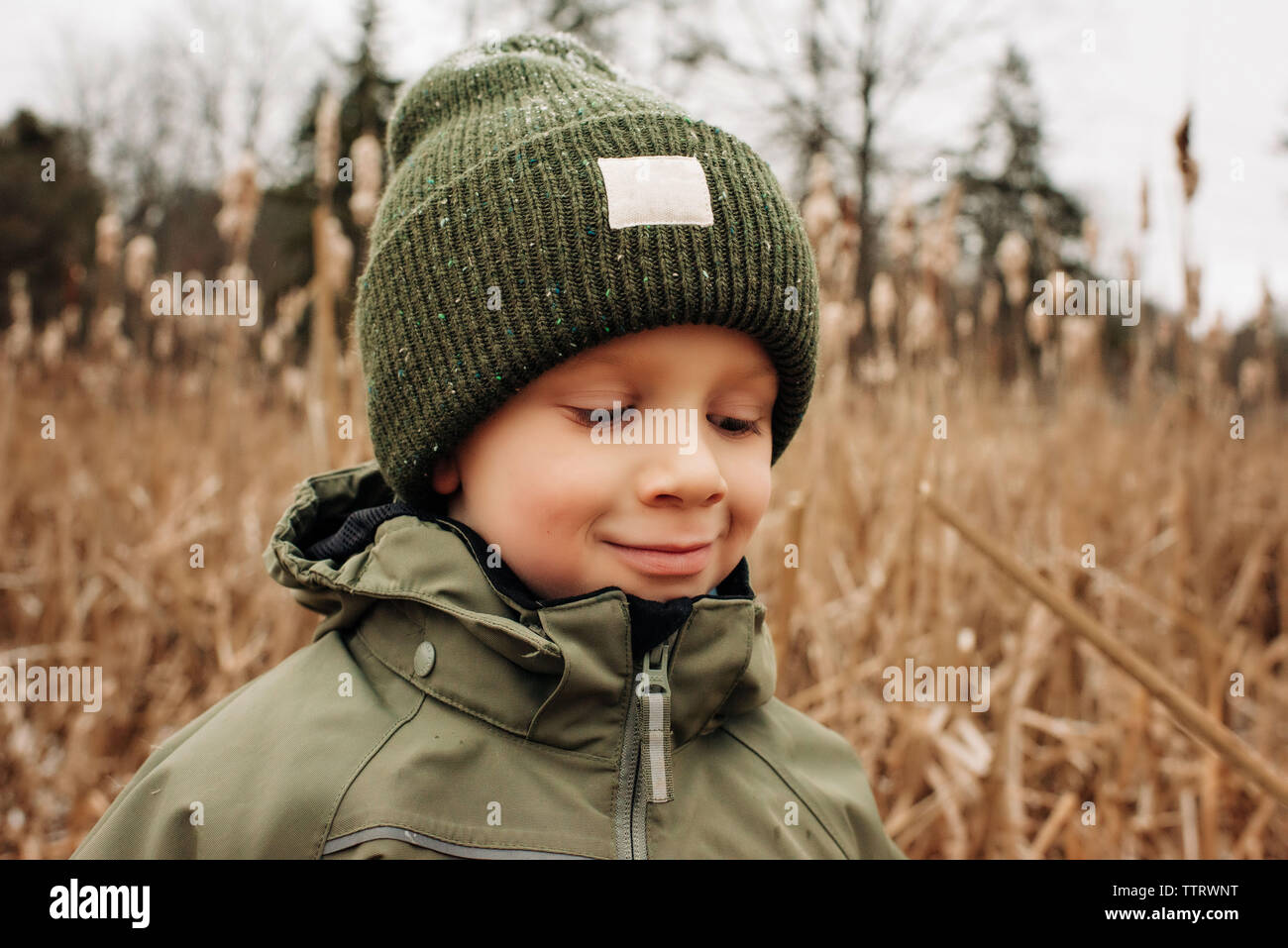 Portrait of young boy smiling en hiver avec chapeau et manteau dans la neige Banque D'Images