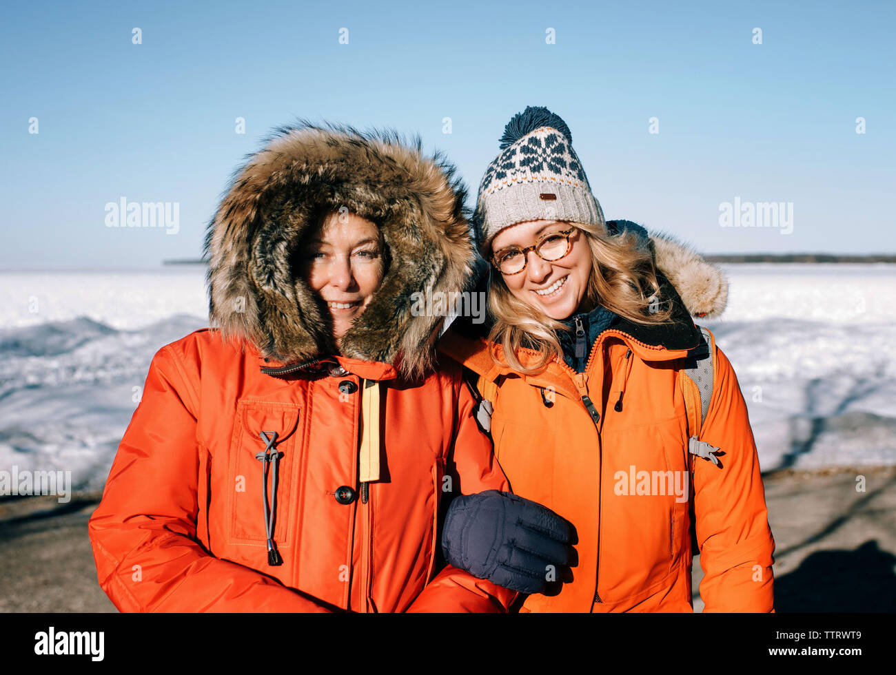 Mère et fille reliant l'extérieur d'armes à la plage en hiver Banque D'Images