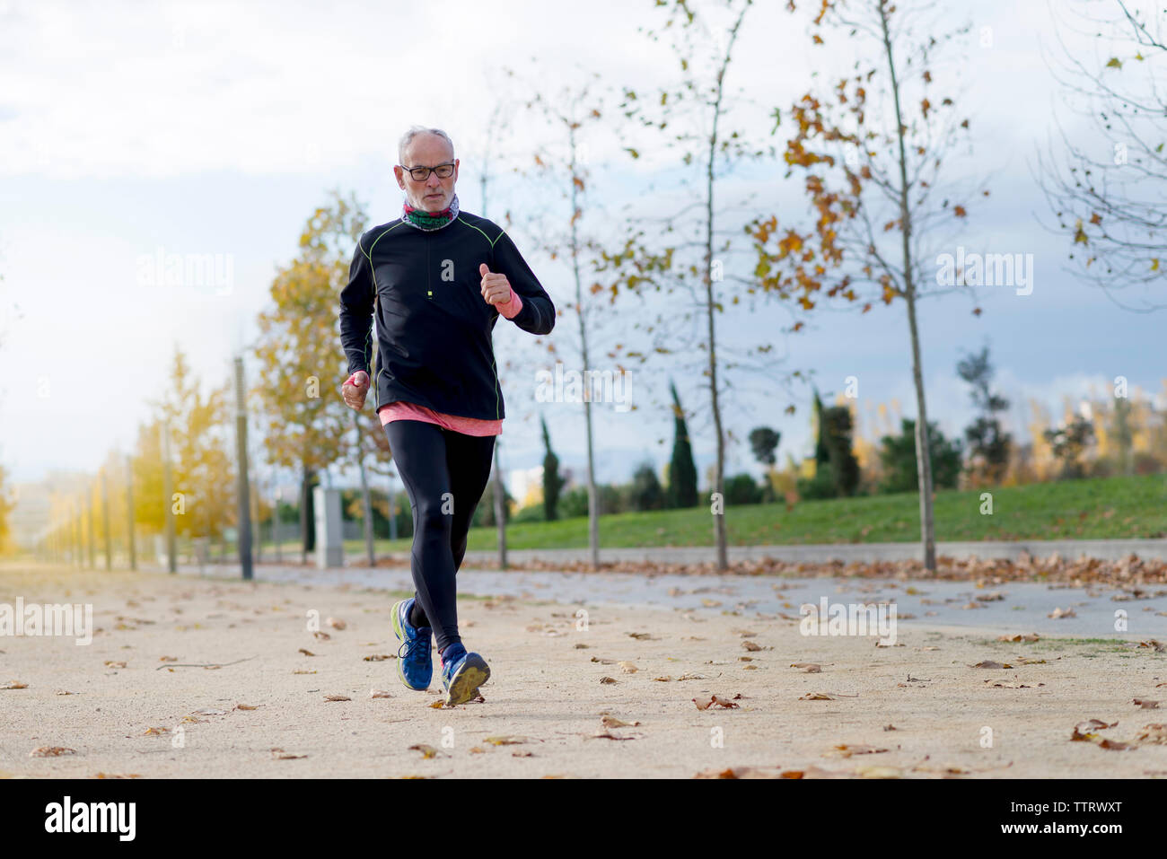 Toute la longueur de senior man jogging tout en exerçant au parc en automne Banque D'Images