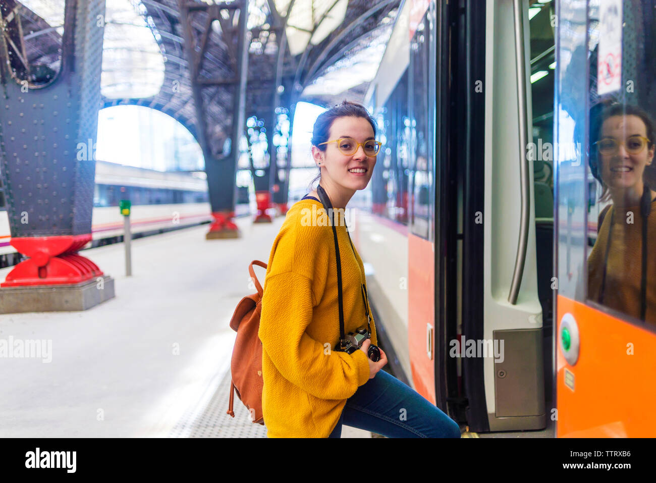 Portrait de jeune femme en sac à dos et l'entrée de l'appareil photo en train à la plate-forme de la gare Banque D'Images