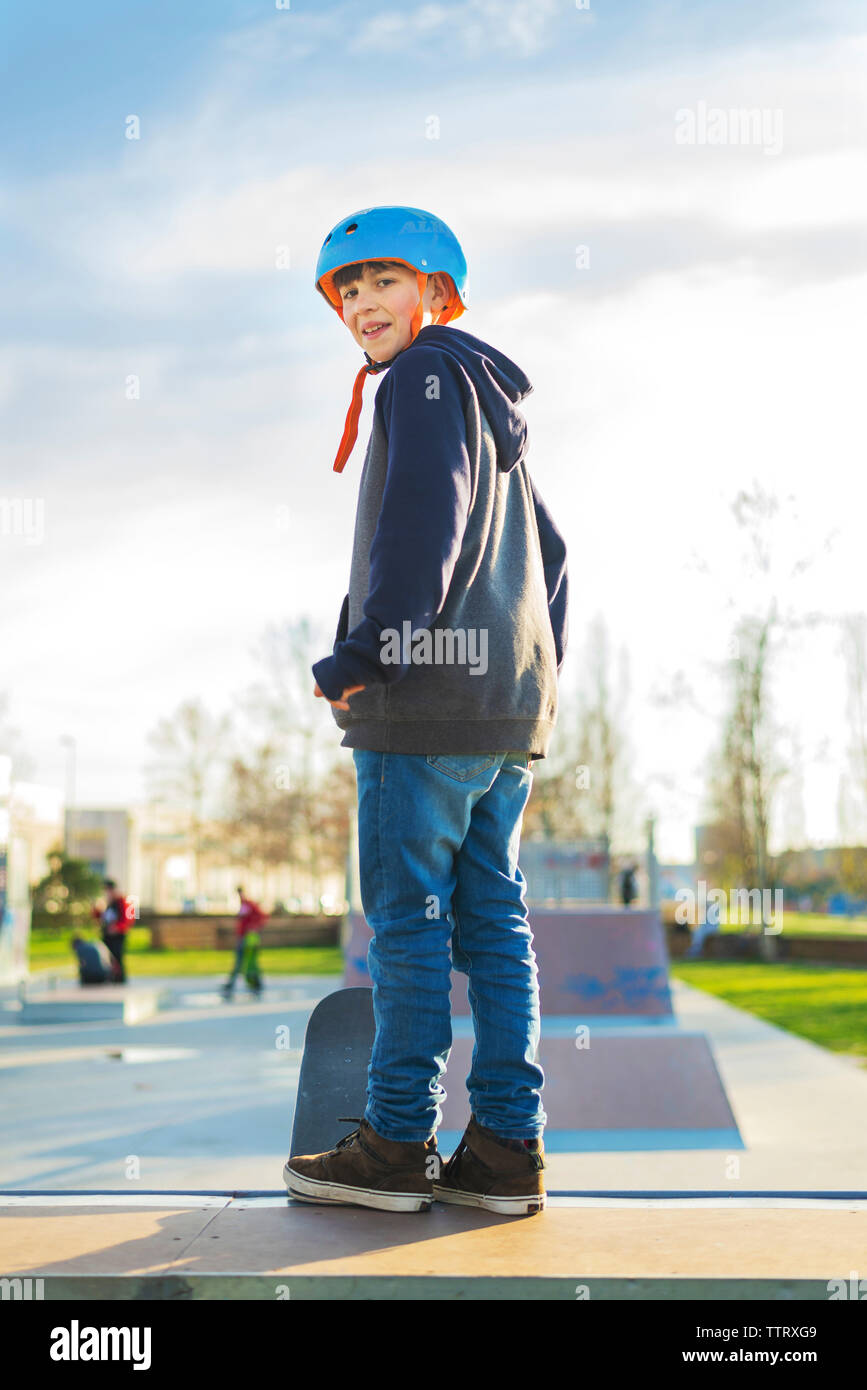 Vue arrière jeune garçon debout à skareramp avant de sourire effectuer trick Banque D'Images