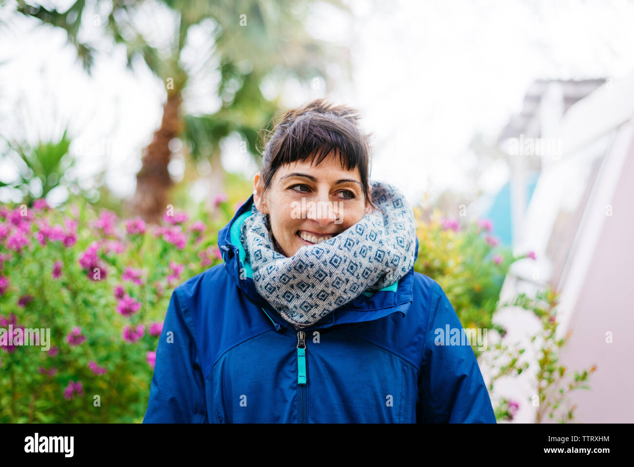 Vue de face of a smiling woman standing outdoors tout en regardant ailleurs Banque D'Images
