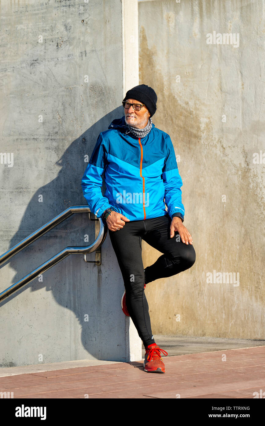 Hauts homme portant des vêtements de sport leaning on wall tout en regardant ailleurs Banque D'Images