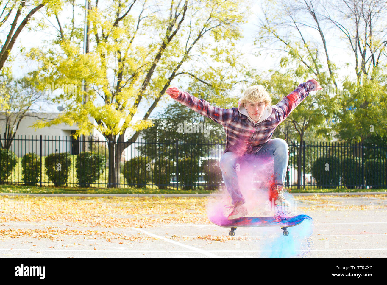 Portrait d'un homme avec la peinture en poudre tout en sautant le skate park au cours de l'automne Banque D'Images