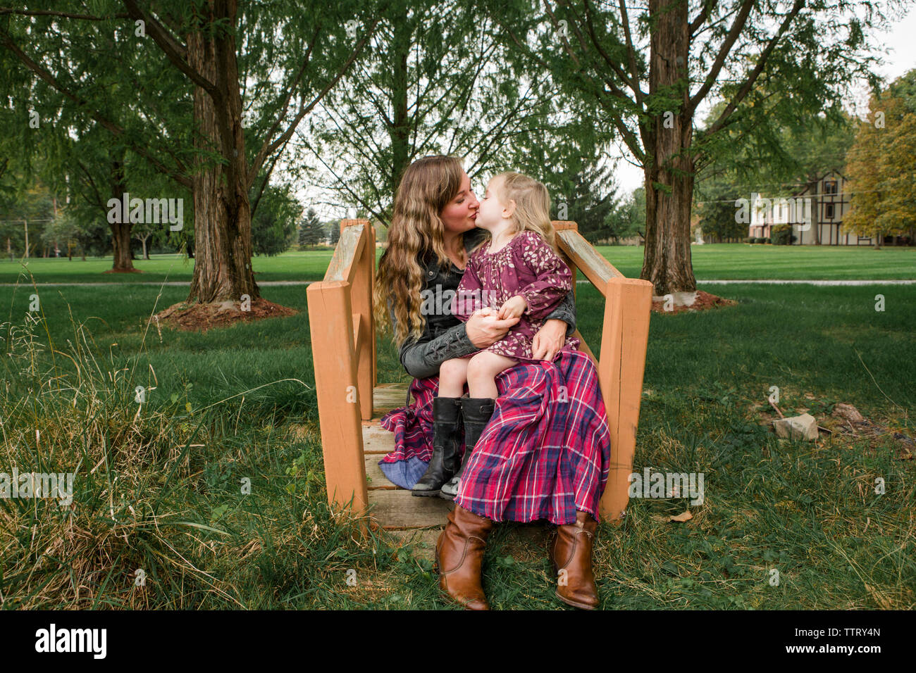Fille mère embrasser tout en restant assis sur ses genoux à park Banque D'Images