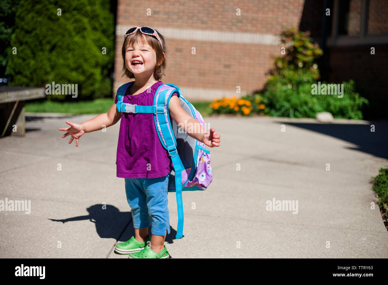 Portrait of happy baby girl avec sac à dos debout sur sentier au cours de journée ensoleillée Banque D'Images