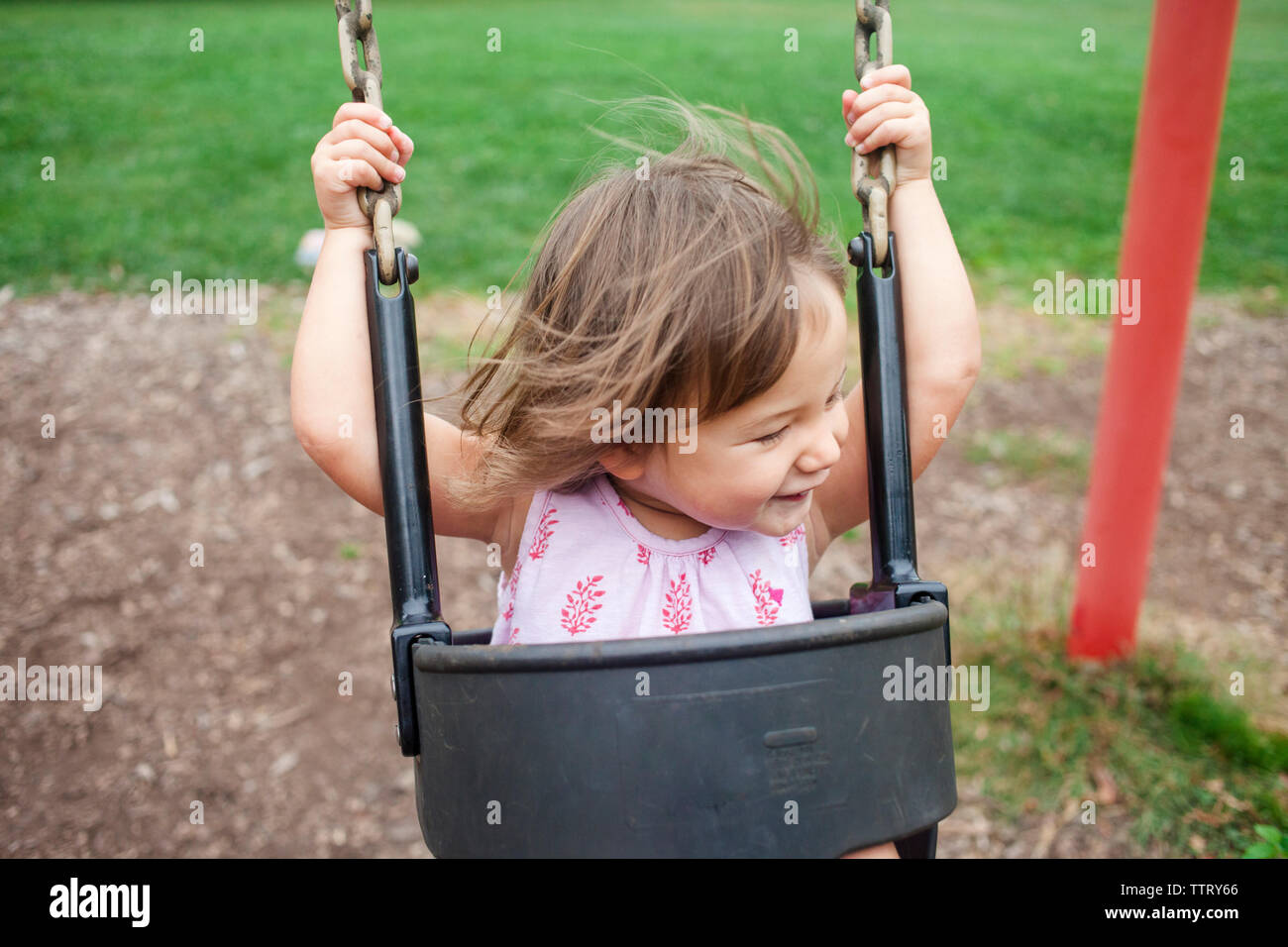Portrait of happy baby fille se balançant à l'aire de jeux Banque D'Images