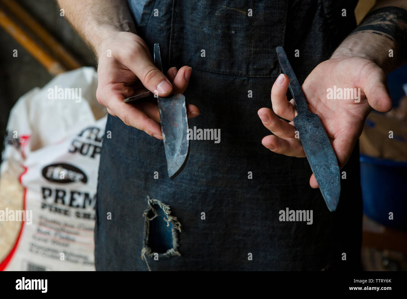 Portrait blacksmith holding couteaux en position debout dans l'atelier Banque D'Images