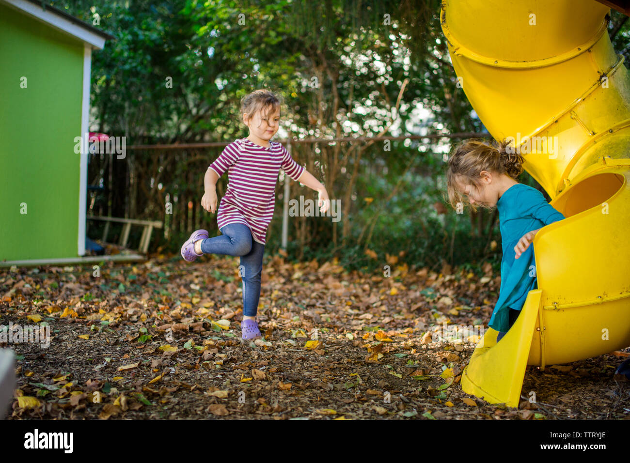 Deux petites filles jouer sur une diapositive de leur cour arrière Banque D'Images