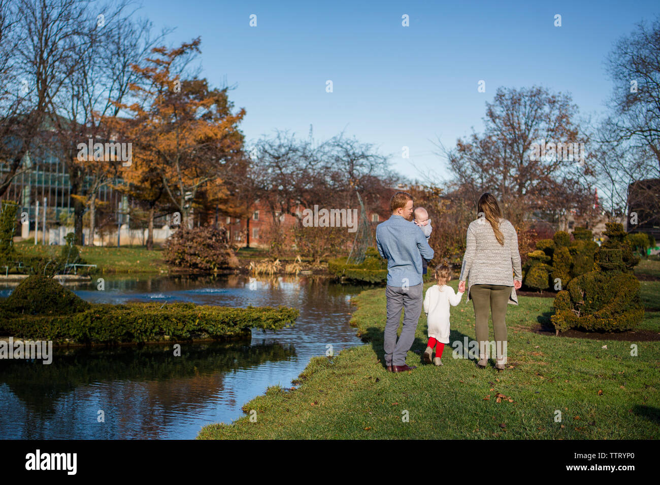 Vue de derrière une famille marcher ensemble dans un parc en automne Sunshine Banque D'Images