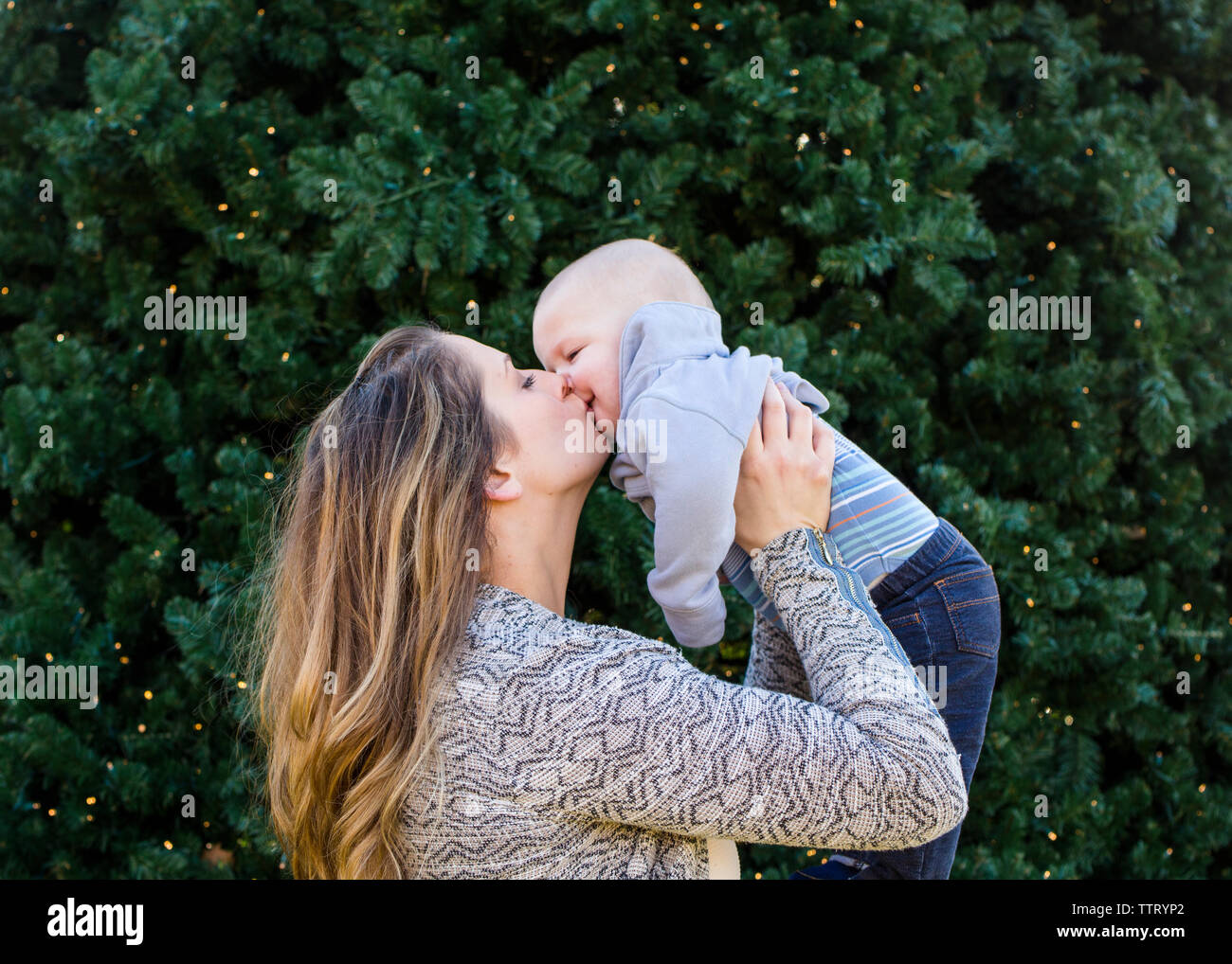 Une mère lève son petit garçon pour un baiser Banque D'Images