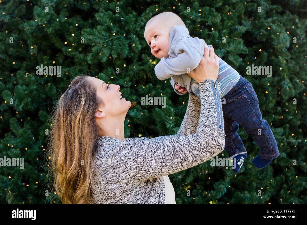 Une mère souriant tendrement lève son petit garçon dans l'air Banque D'Images