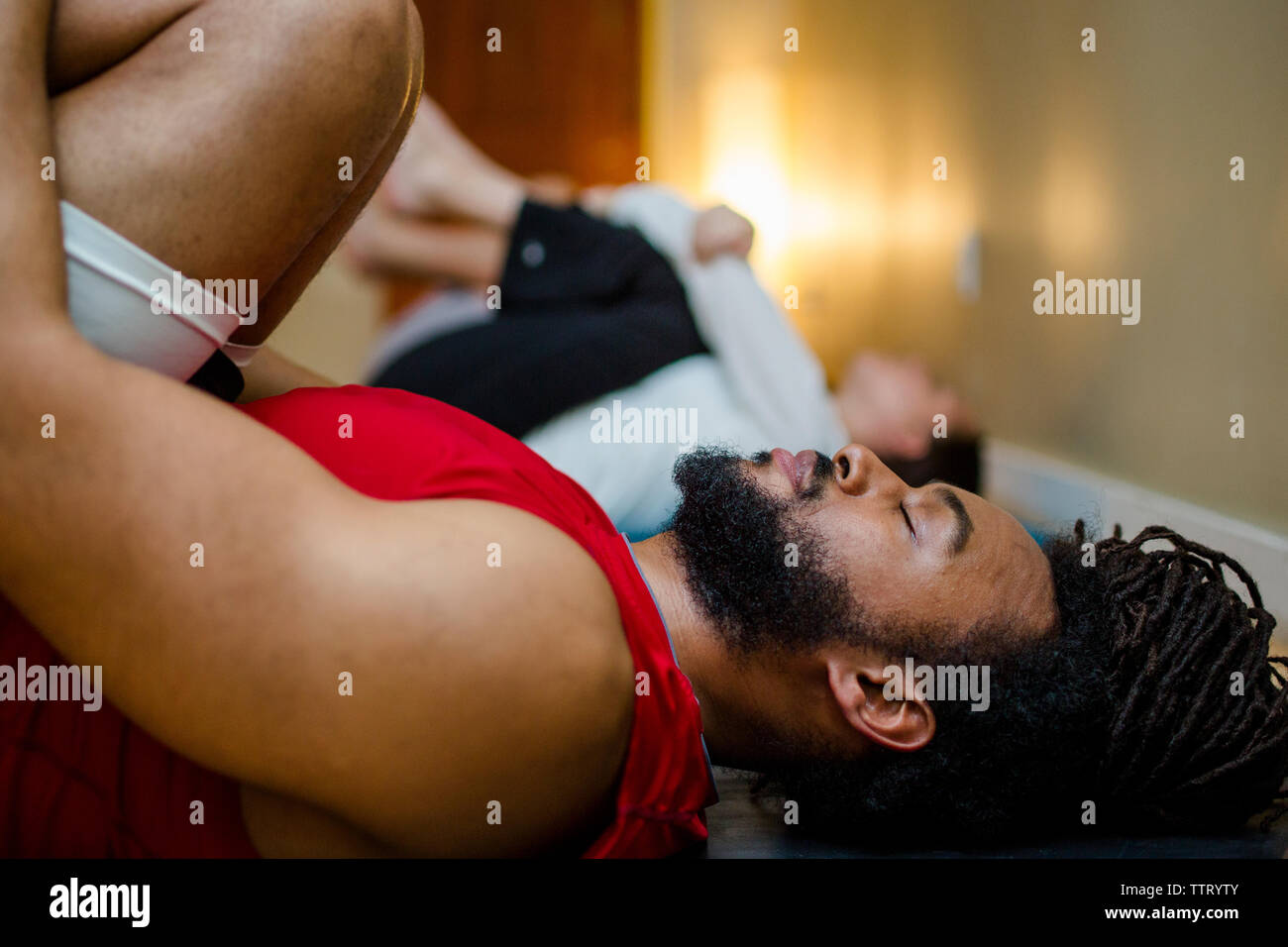 Un homme pacifique se détend sur son dos dans une classe de yoga Banque D'Images