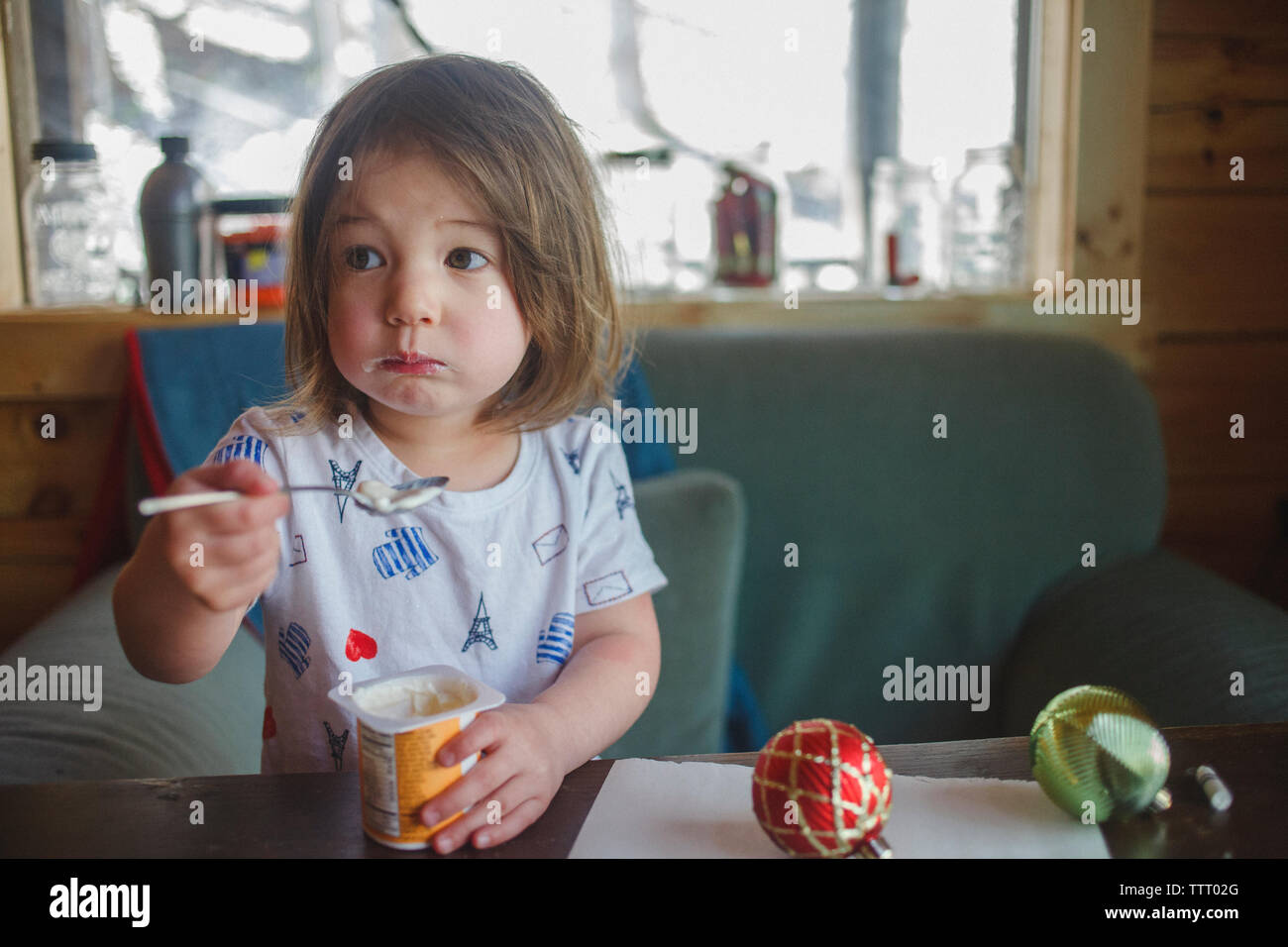 Portrait of a cute little Girl with messy bouche eating breakfast Banque D'Images