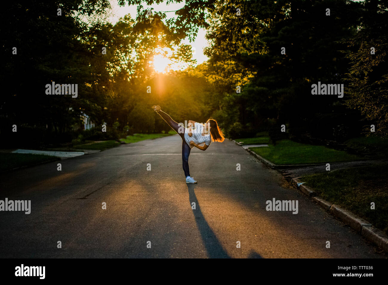 Une adolescente effectue les arts martiaux kick sur street au coucher du soleil Banque D'Images