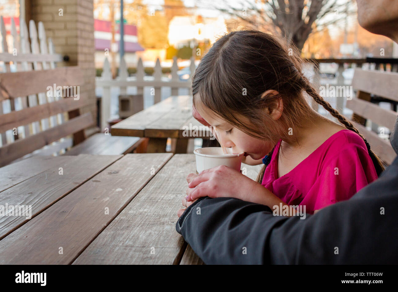 Une jeune fille de sips cup à un café en plein air et tient la main de père Banque D'Images
