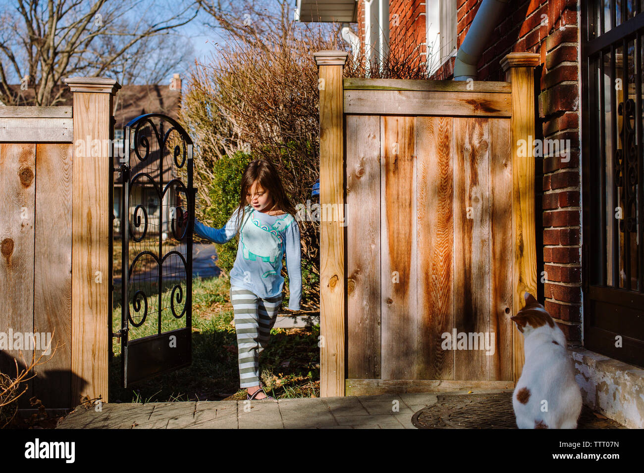 Une petite fille marche dans une cour porte vers cat en attente Banque D'Images
