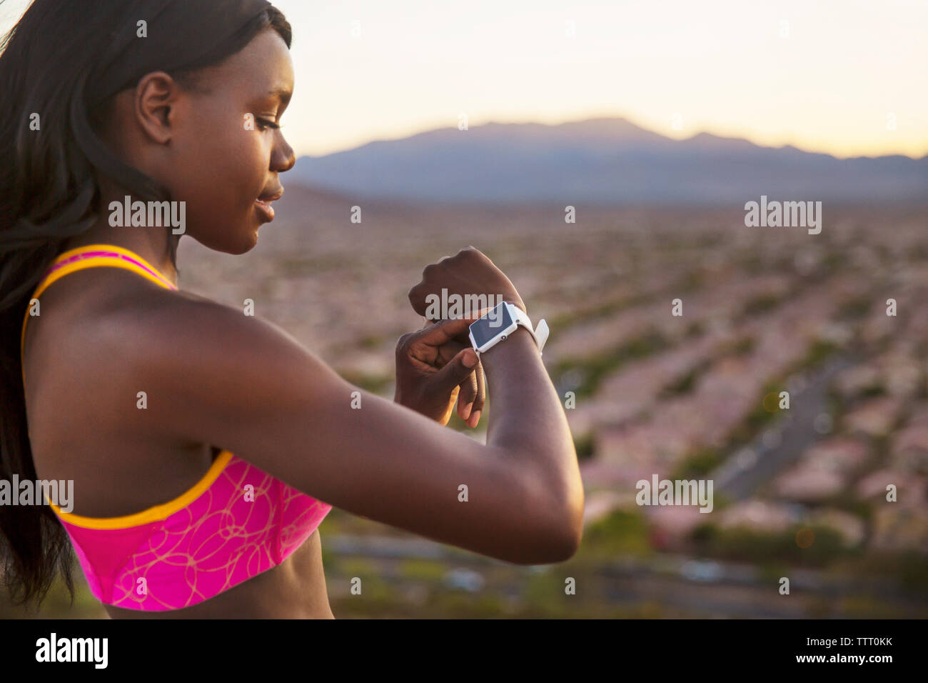 Vue latérale du contrôle de l'athlète féminine montre-bracelet contre village Banque D'Images