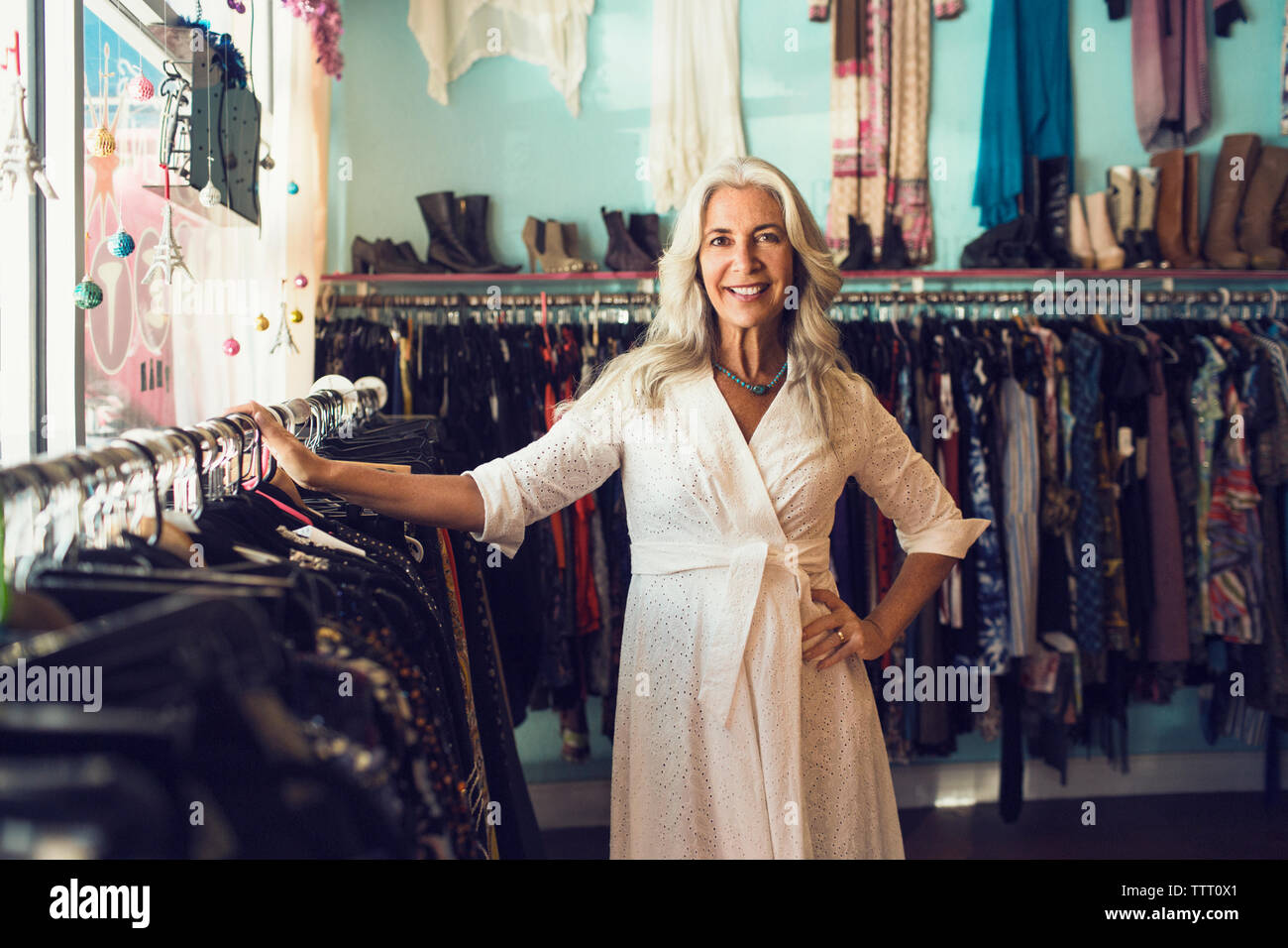 Portrait of smiling femme propriétaire par rack de vêtements en magasin Banque D'Images