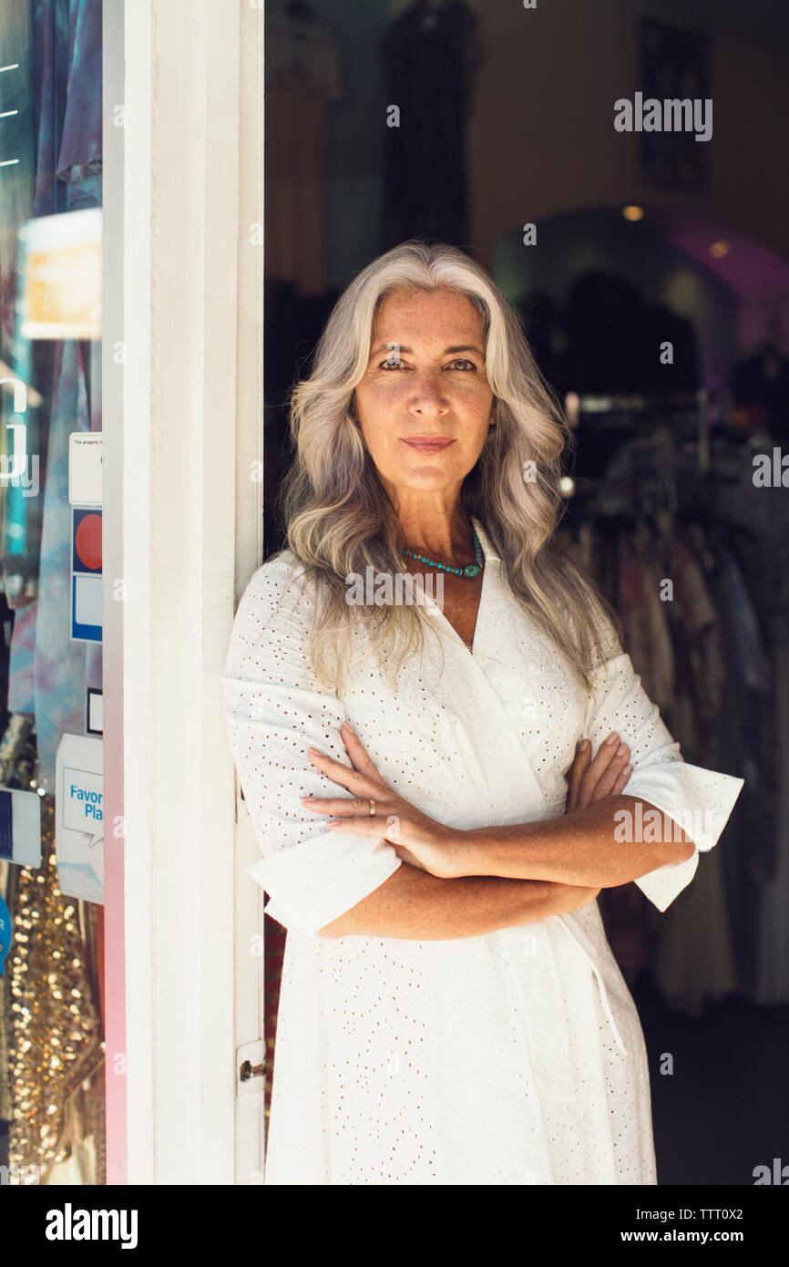 Portrait de femme entrepreneur debout les bras croisés à l'entrée du magasin de vêtements Banque D'Images