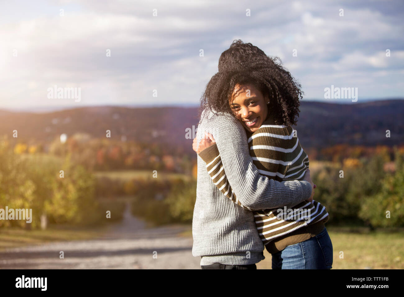 Portrait of woman embracing boyfriend debout contre sky in orchard Banque D'Images