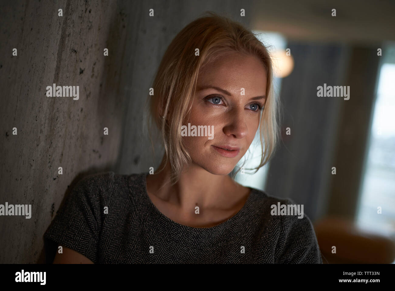 Thoughtful woman loin tout en s'appuyant sur mur à chambre d'hôtel Banque D'Images