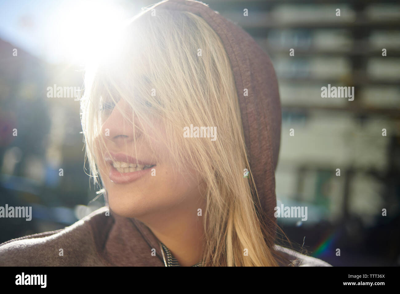 Close-up of woman with Blonde hair wearing hooded shirt tout en se tenant dans la ville pendant les jours ensoleillés Banque D'Images