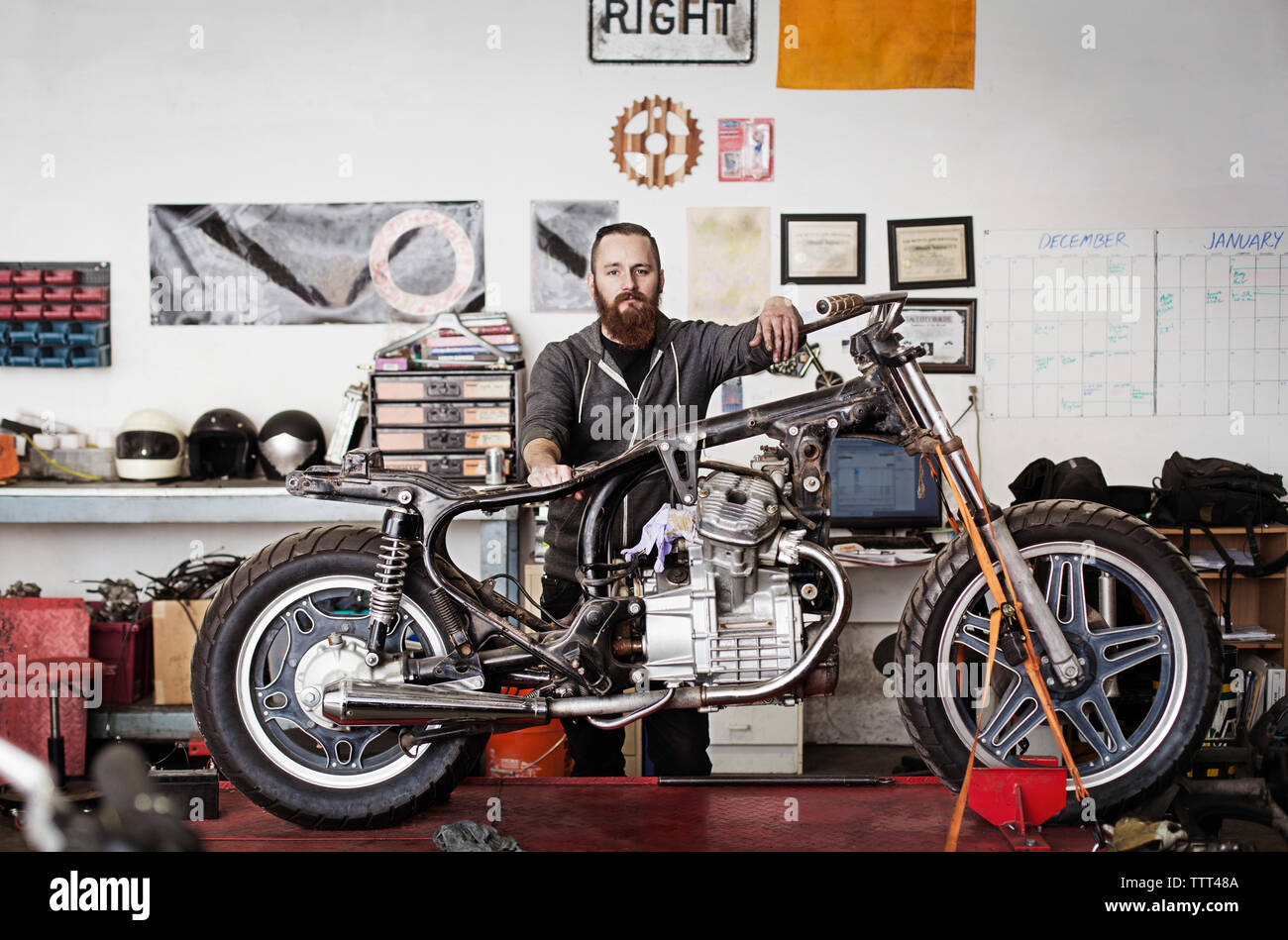 Portrait of smiling mechanic standing à moto avec auto repair shop Banque D'Images