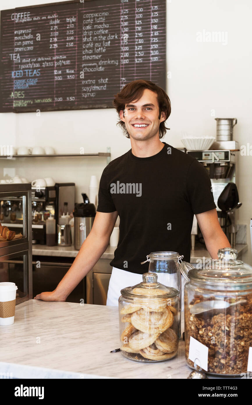 Portrait d'heureux propriétaire debout au comptoir du magasin Banque D'Images