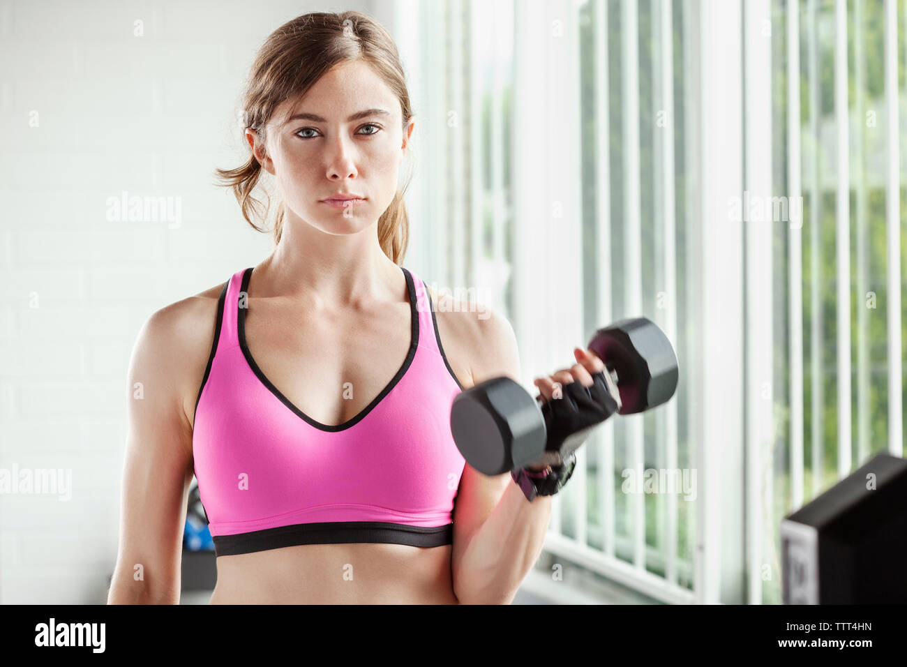 Portrait of woman lifting dumbbell at gym Banque D'Images