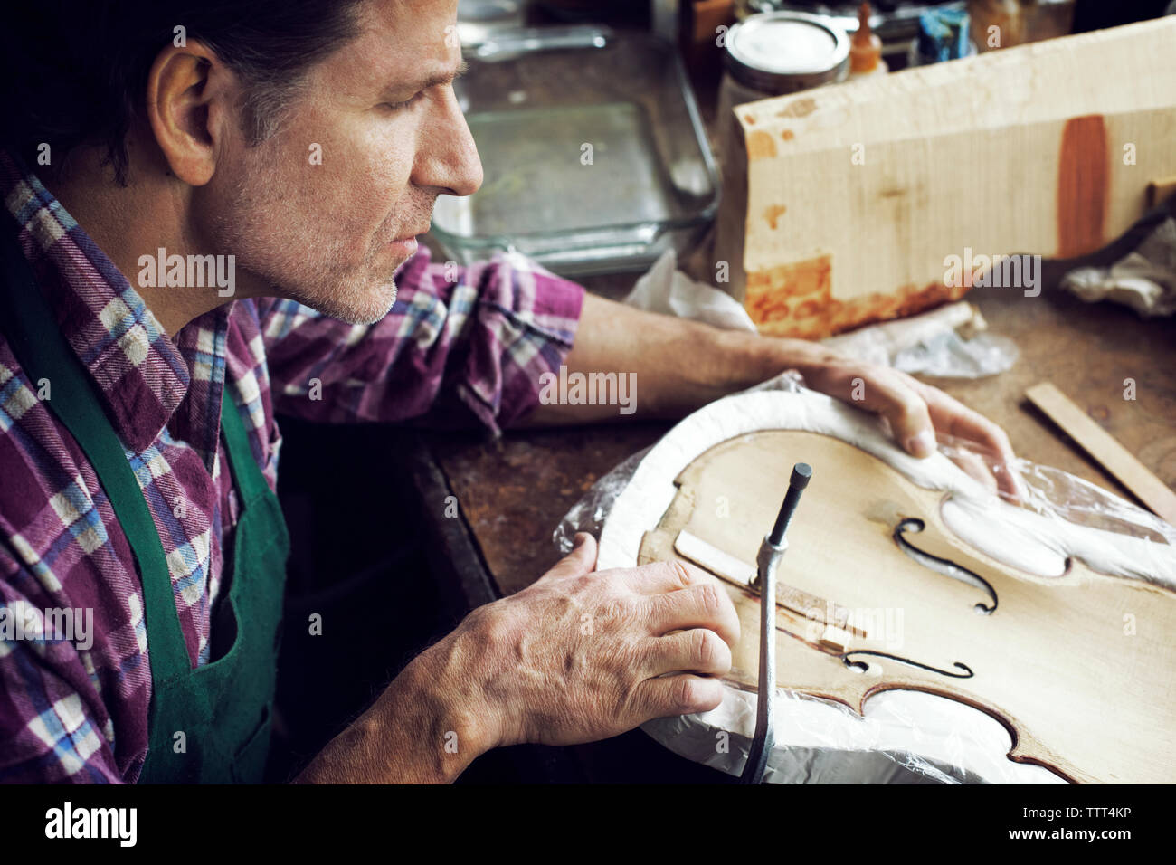 High angle view of man making violin in workshop Banque D'Images