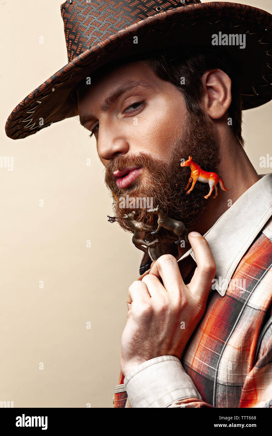 Jeune homme dans un chapeau de cowboy et toy horses in a beard Banque D'Images