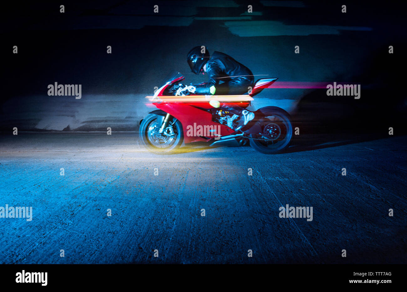Biker riding on road by wall Banque D'Images