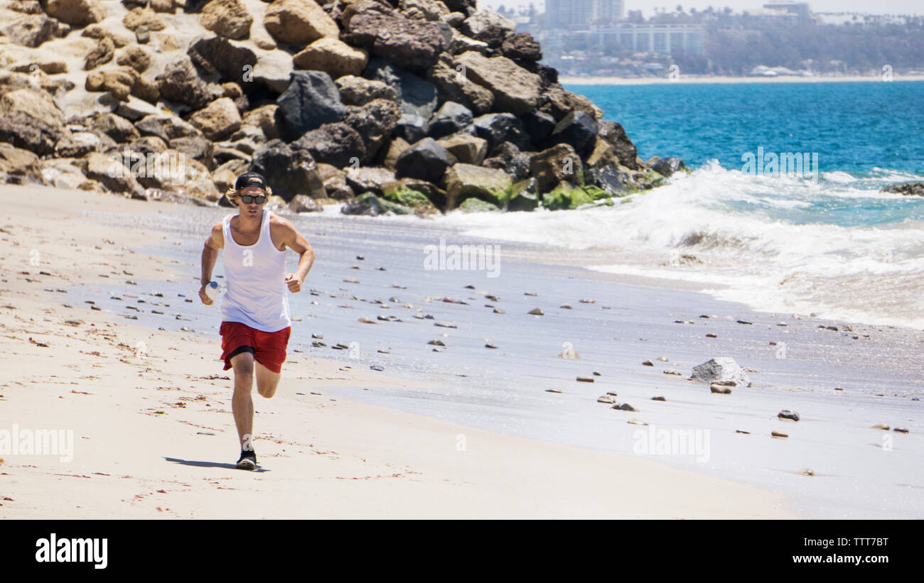 L'Homme à lunettes de courir sur la plage sunny day Banque D'Images