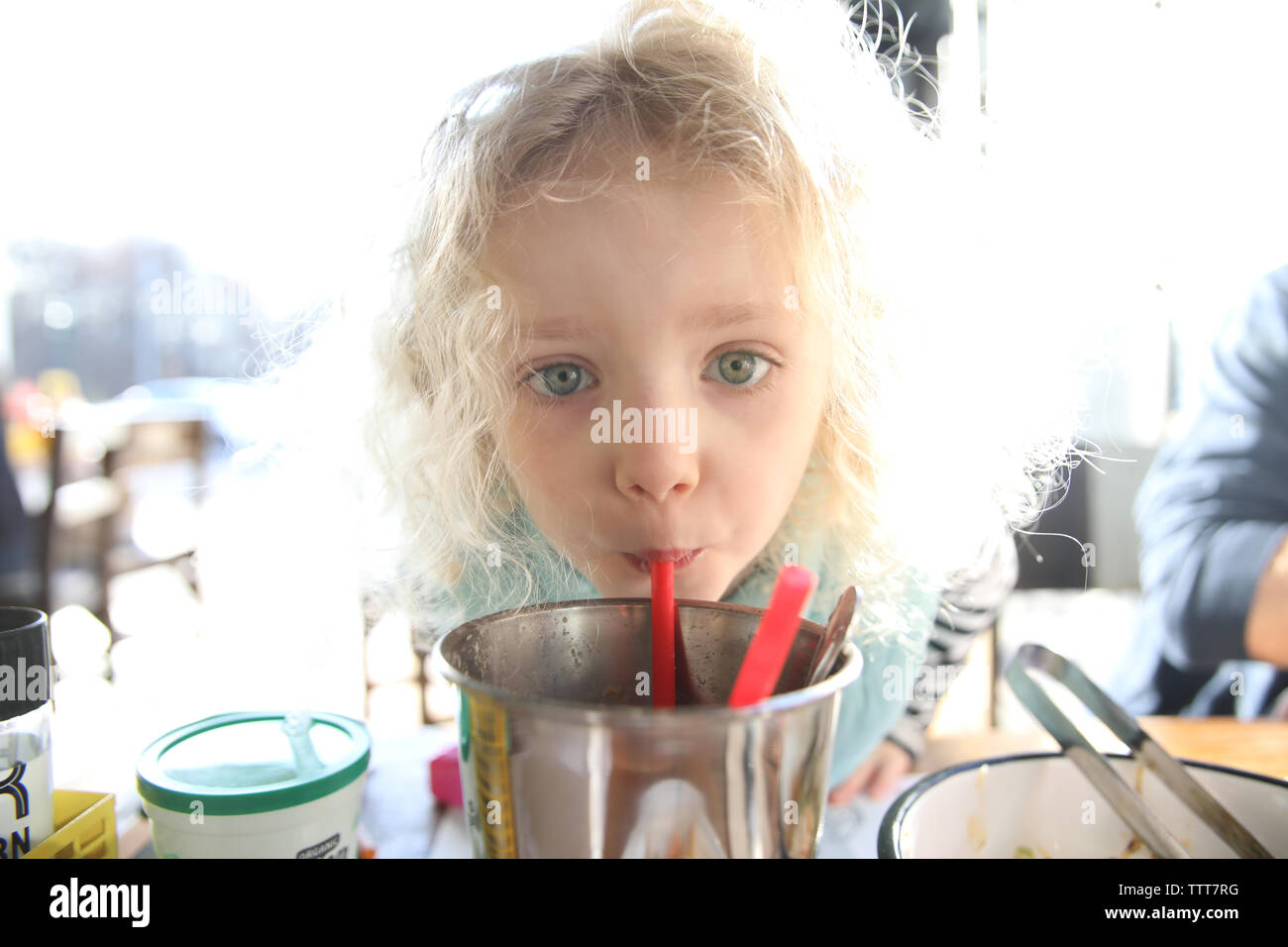 Close-up portrait of girl drinking de récipient dans un restaurant éclairé lumineux Banque D'Images