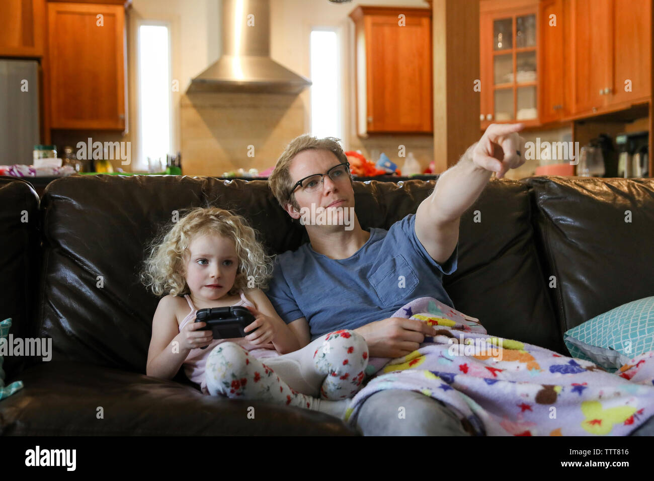 Tout en pointant le Père fille jouer jeu vidéo sur canapé à la maison Banque D'Images