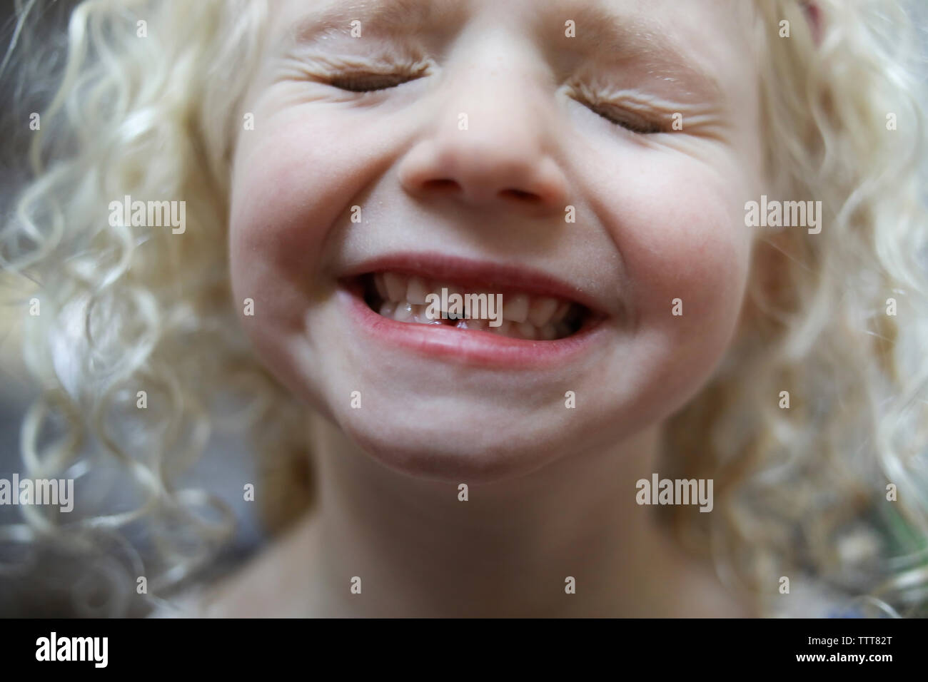 Close-up of playful girl avec les yeux fermé montrant ses dents gap Banque D'Images