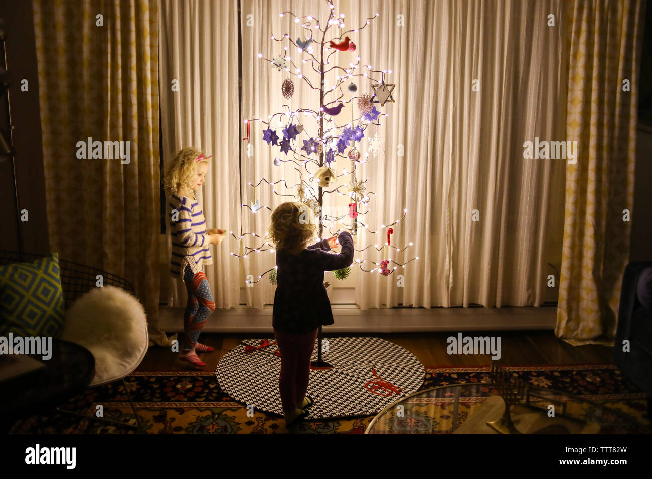 Soeurs décorant le sapin de noël artificiel à la maison Banque D'Images