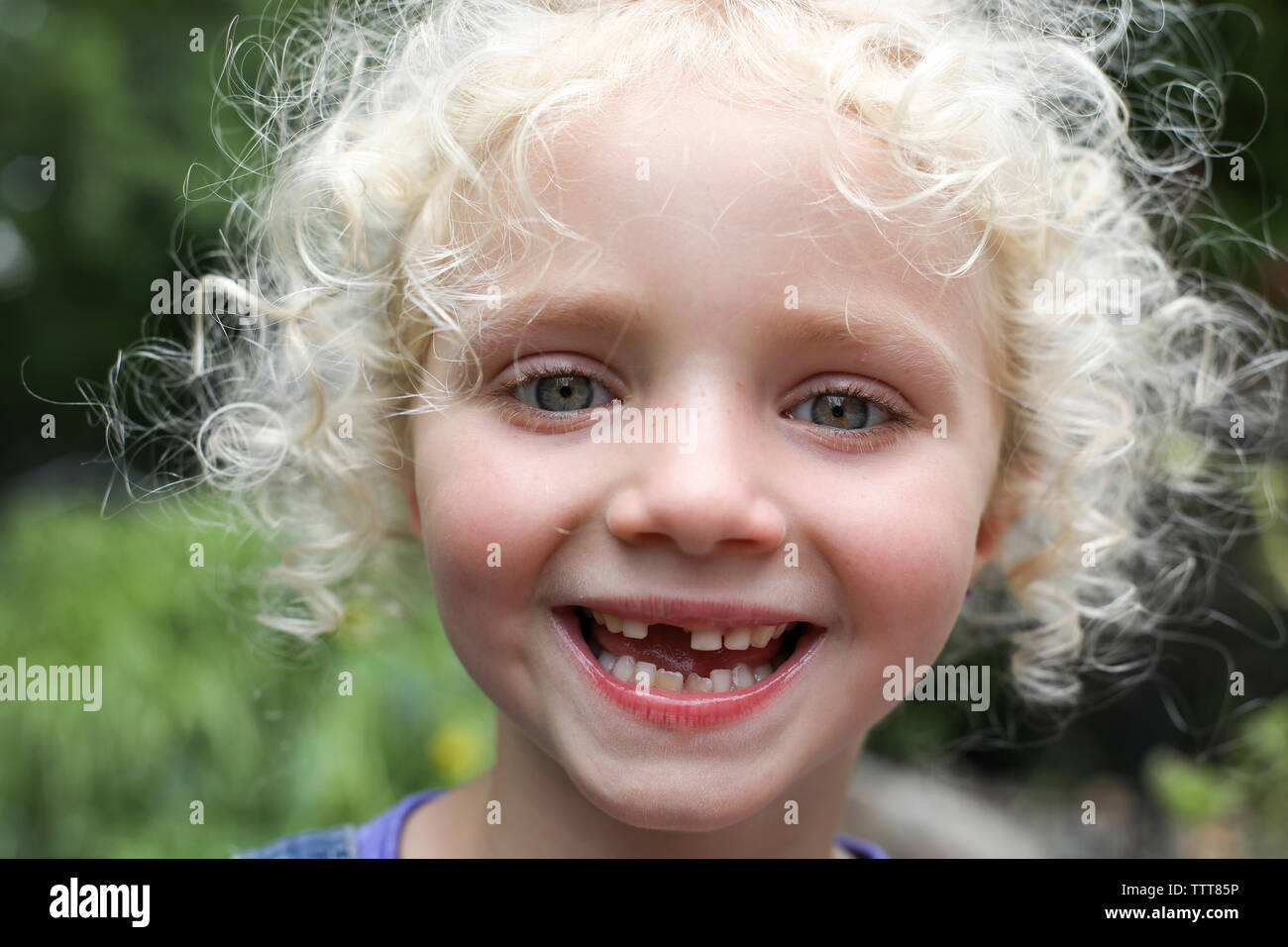Close-up portrait of happy girl avec des cheveux blonds en désordre à la cour permanente Banque D'Images