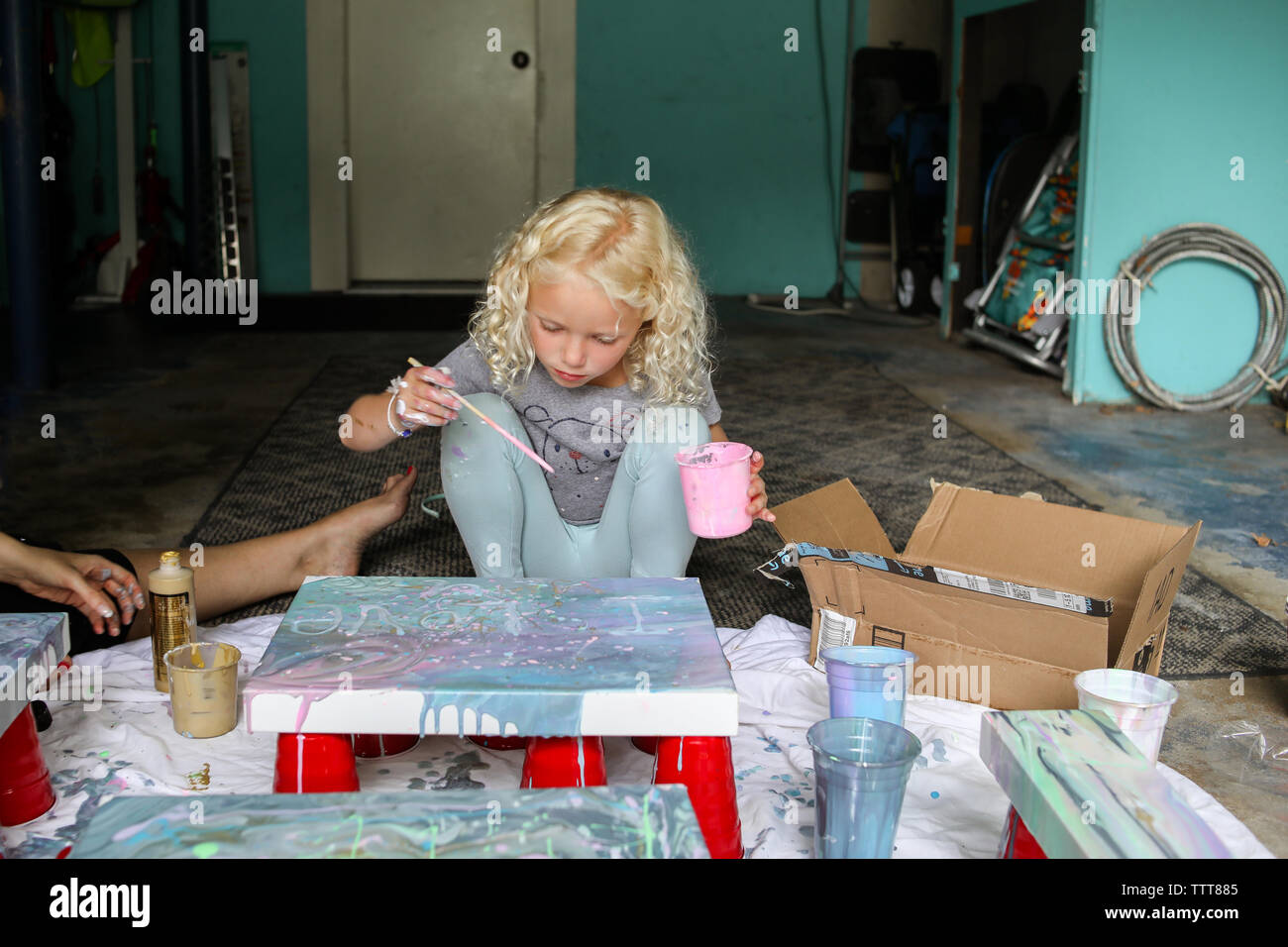 Jeune fille la création d'œuvres sur toile à l'aide d'un pinceau en garage Banque D'Images