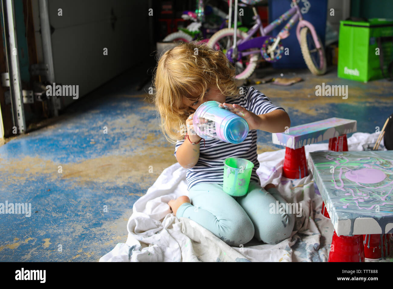 Petite fille de la peinture de tasse en garage crée de l'art Banque D'Images