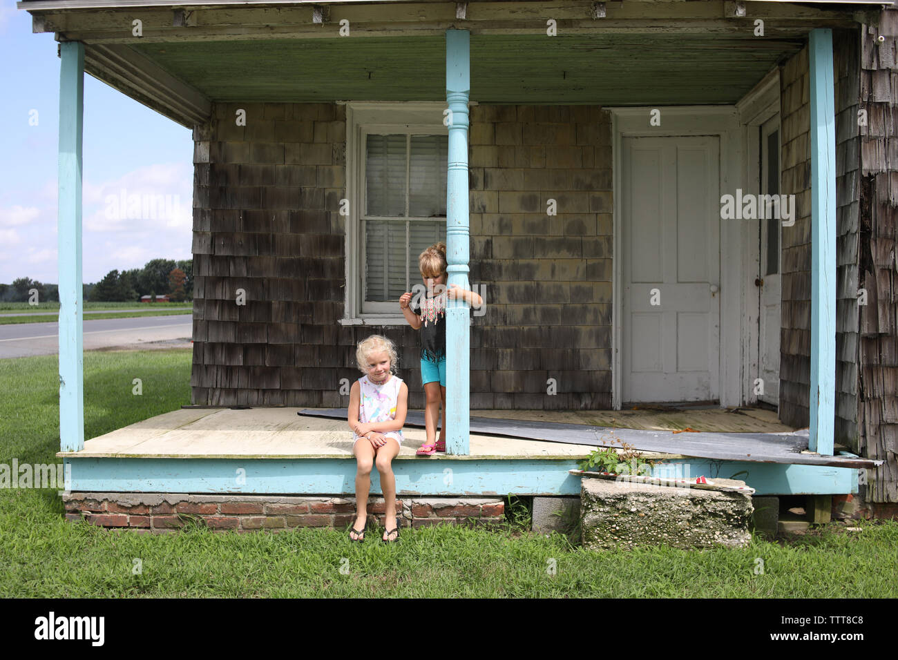 Soeurs assis sur portique de l'ancien accueil sur le côté de la route en été Banque D'Images