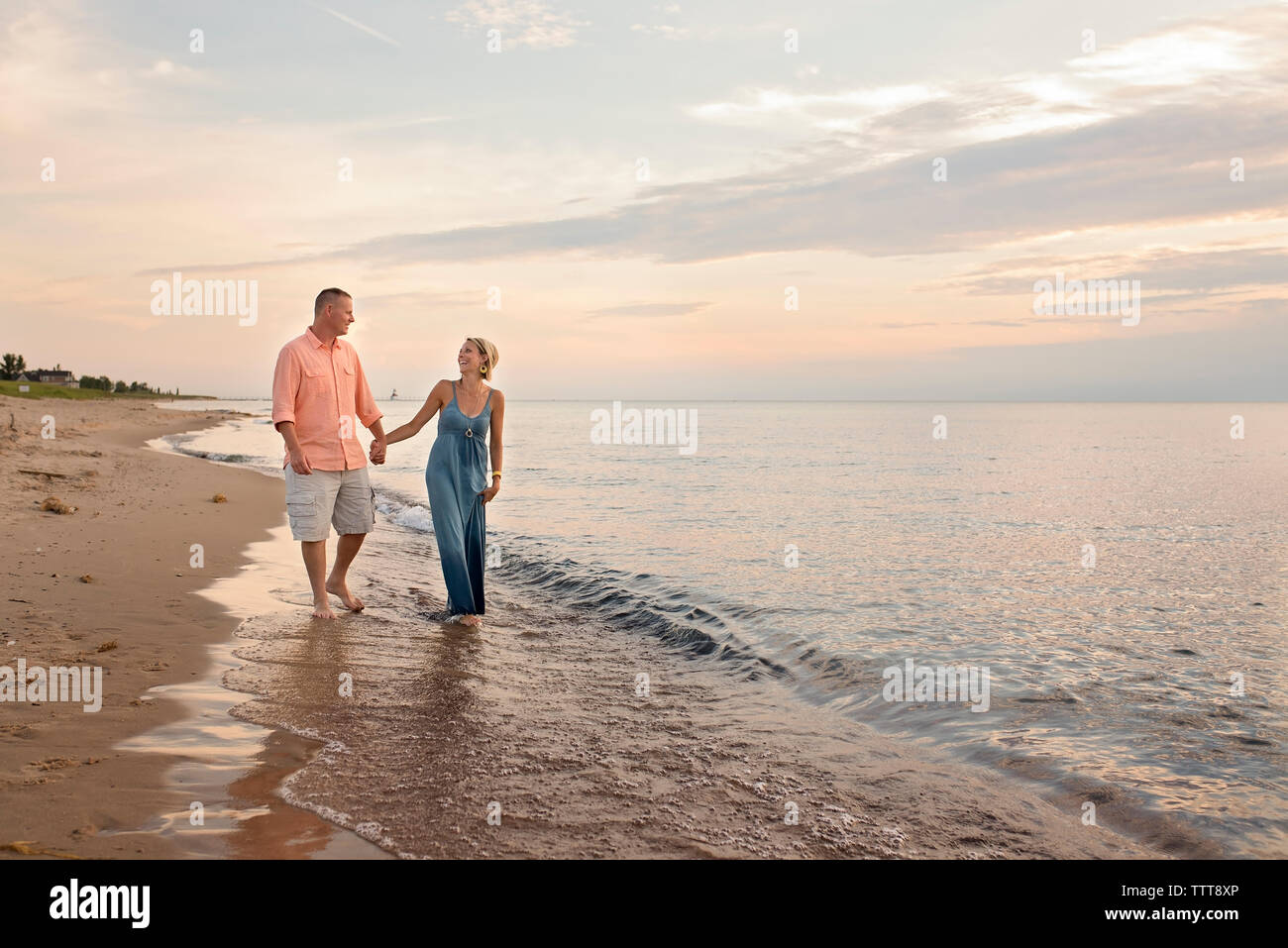 Couple d'amoureux se tenant la main tout en marchant sur le rivage à Beach pendant le coucher du soleil Banque D'Images