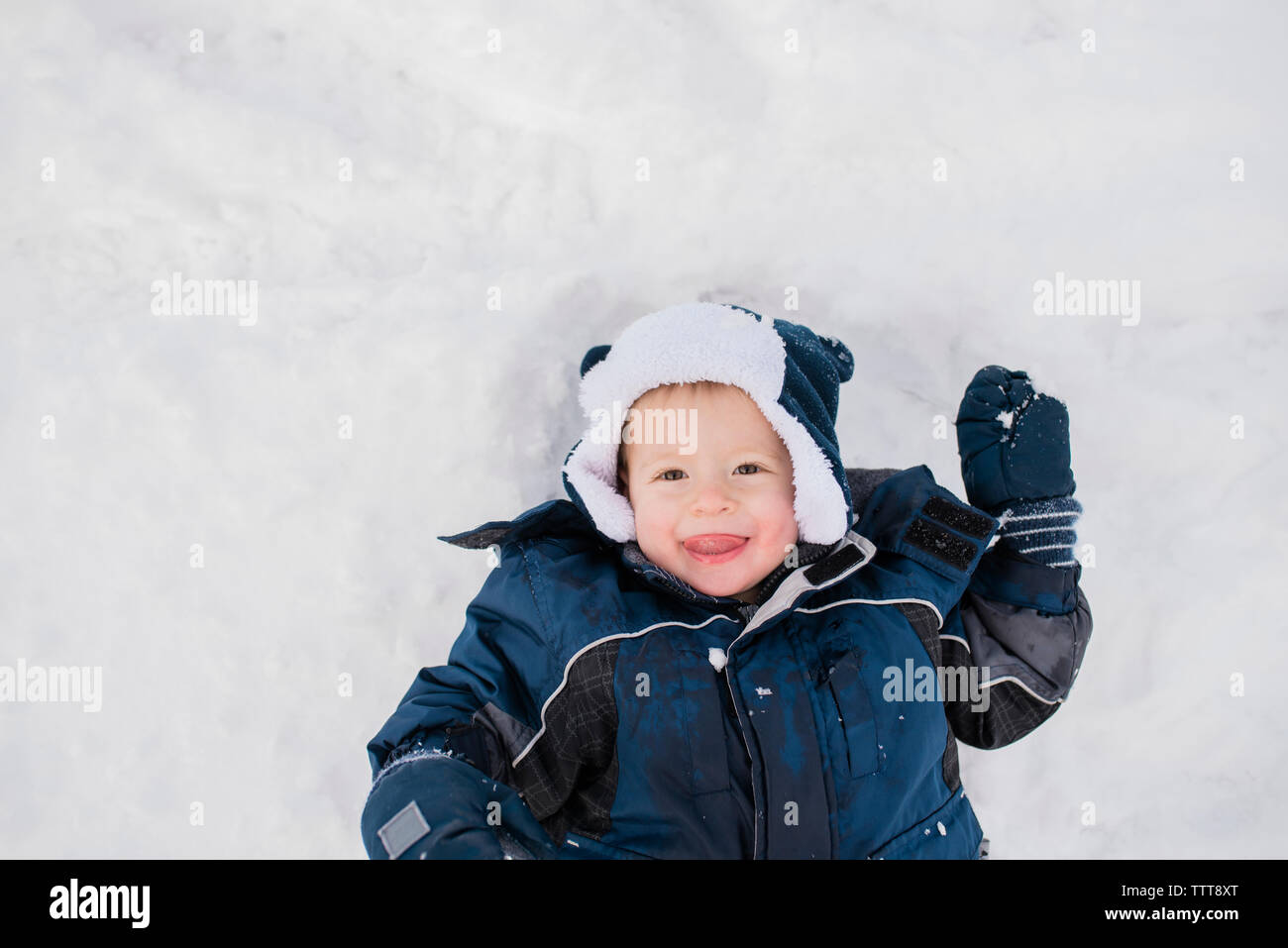 Passage portrait of cute baby boy lying on snow Banque D'Images