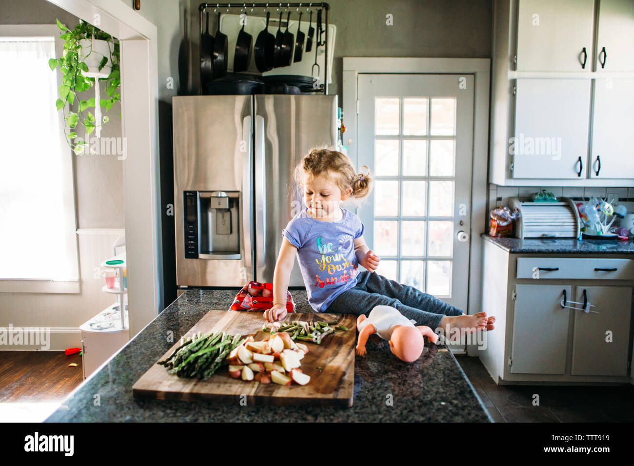 Fille assise par aliments hachés sur une planche à découper cuisine à Banque D'Images
